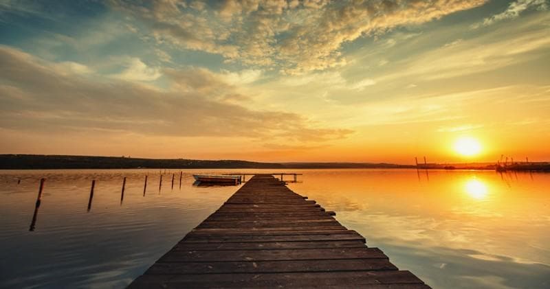 Golden sunset over a wooden pier and calm coastal bay