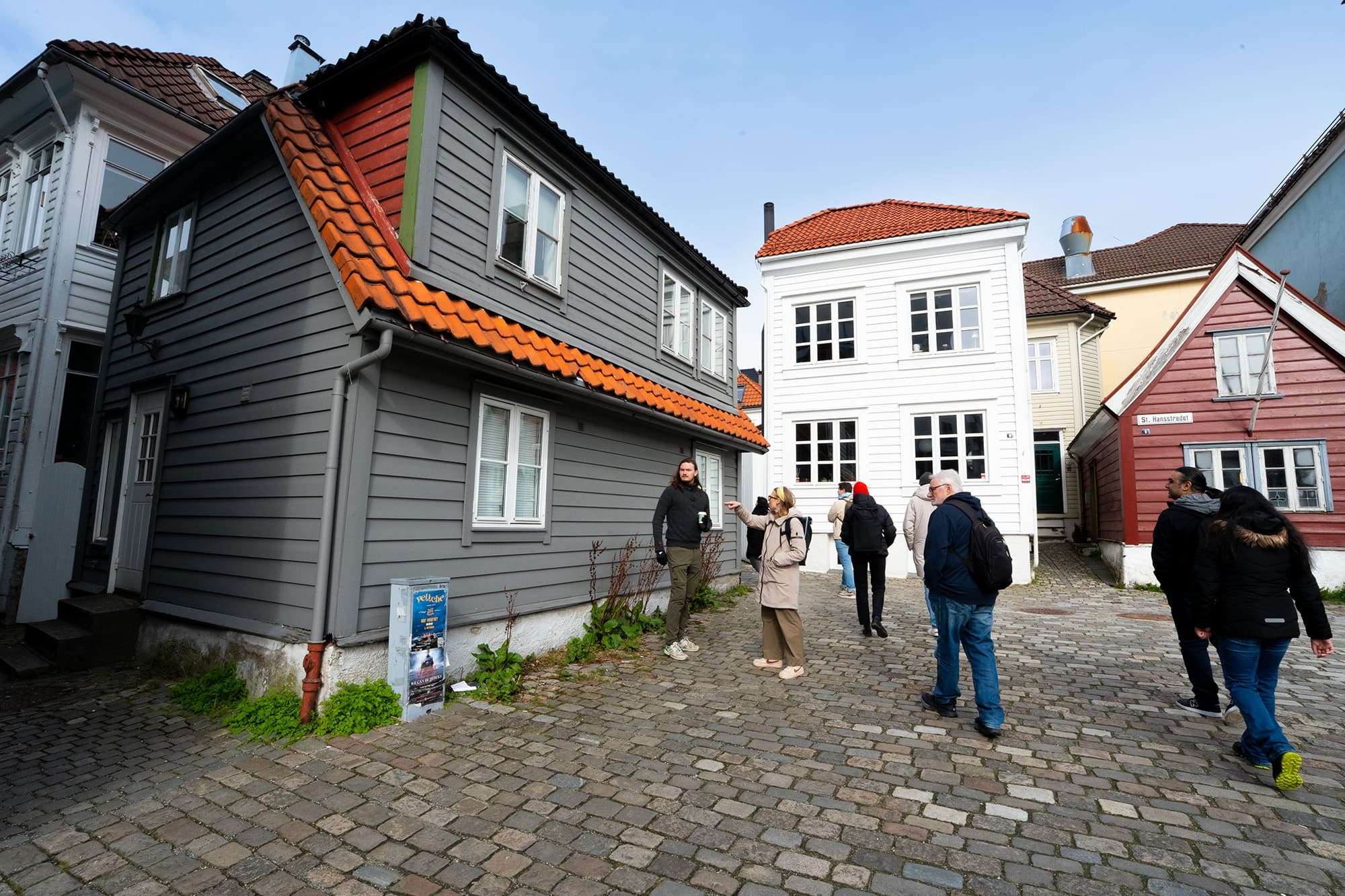 Walking tour on cobblestone street past wooden Bergen houses