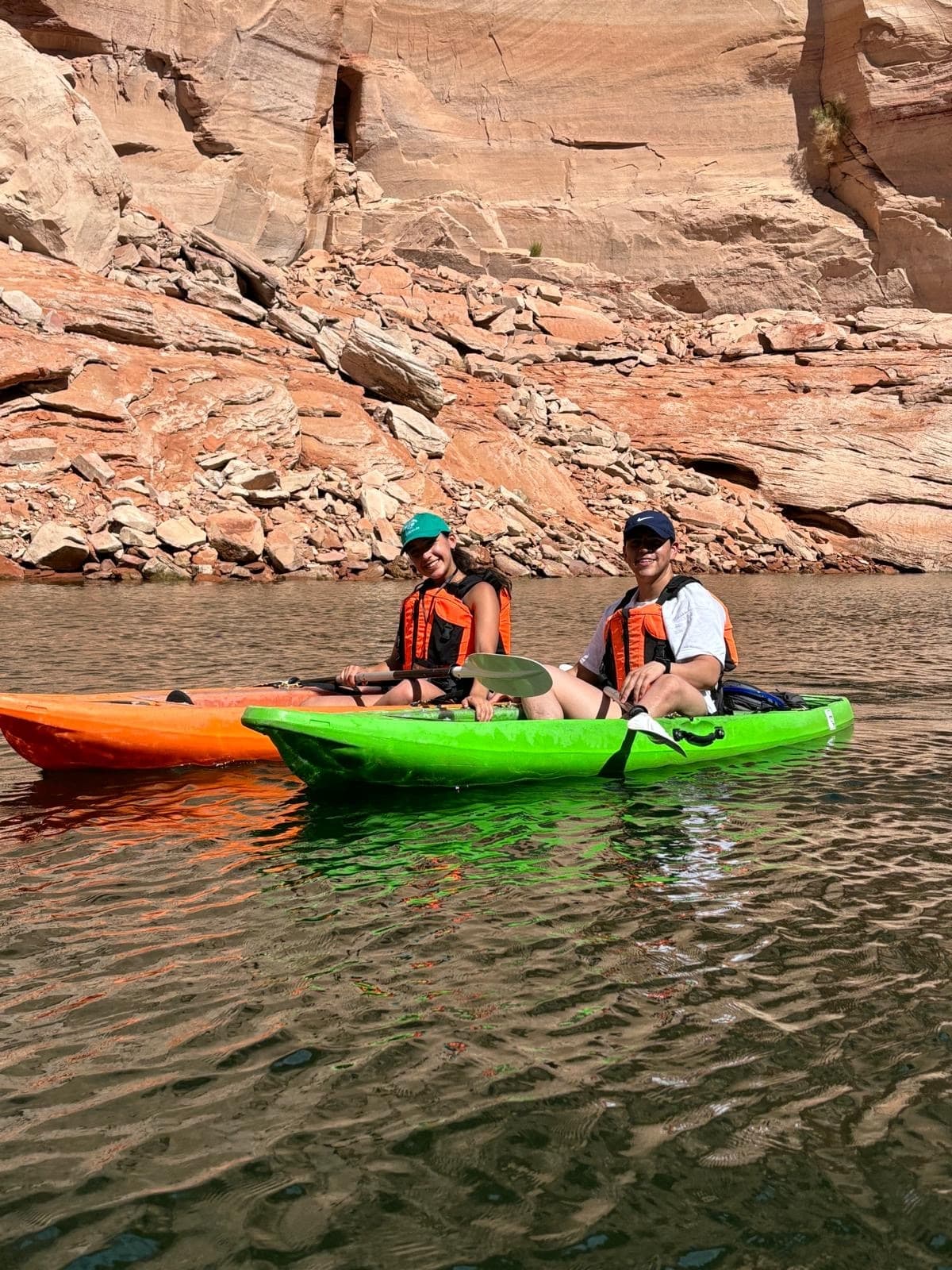 Two kayakers paddling calm canyon waters in inflatable kayaks