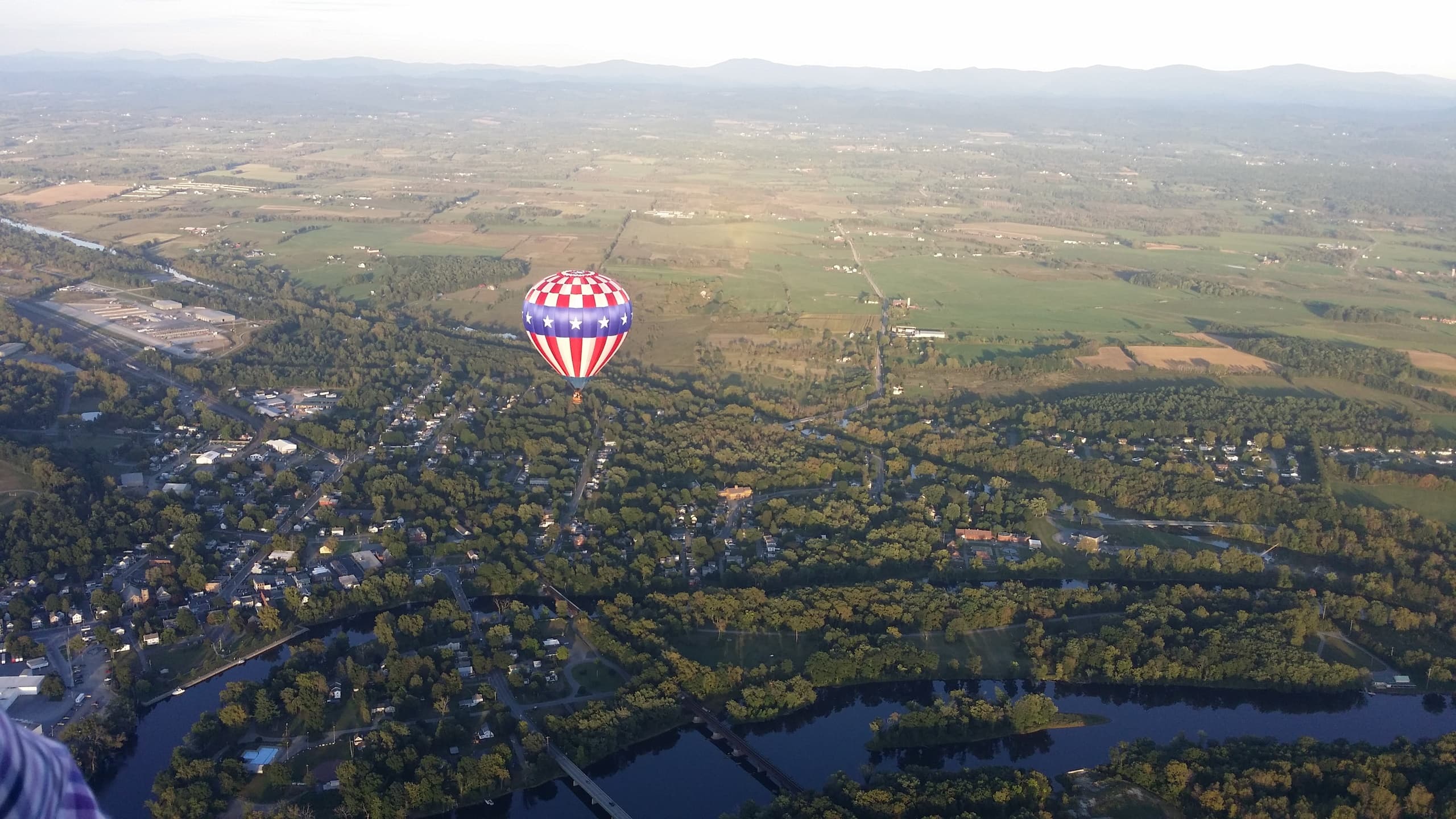 Aerial view of single hot air balloon above small town landscape