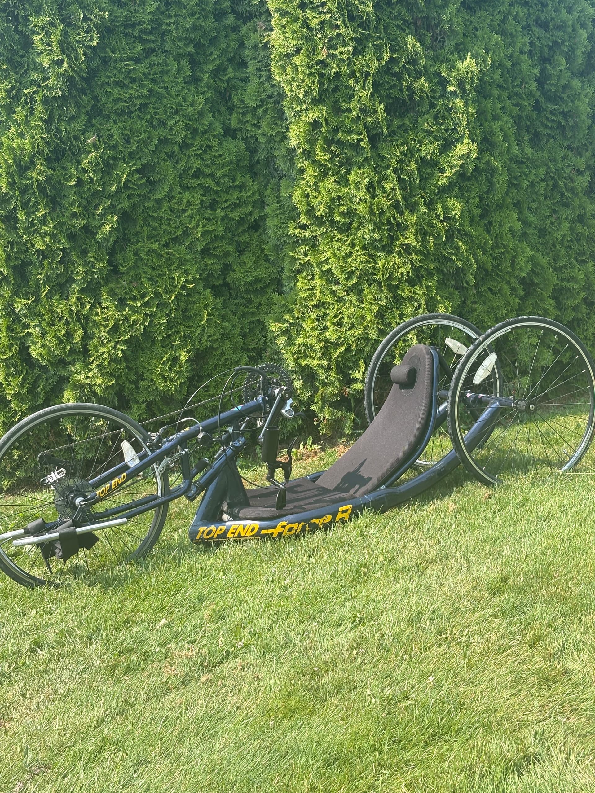 Black reclined handcycle on grass, adaptive outdoor racing setup