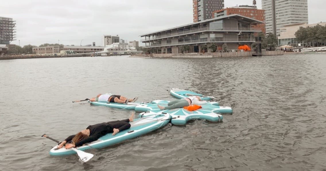 Paddleboarders relaxing on boards in city waterfront near docks