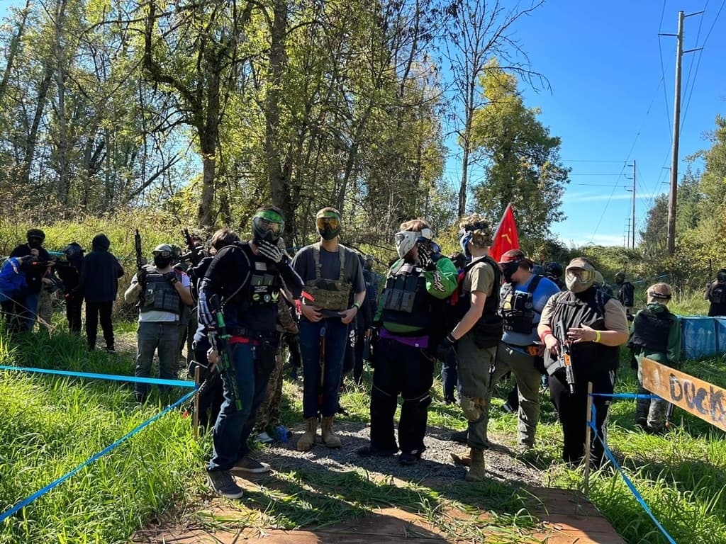 Outdoor woodland paintball group gathering on grassy field
