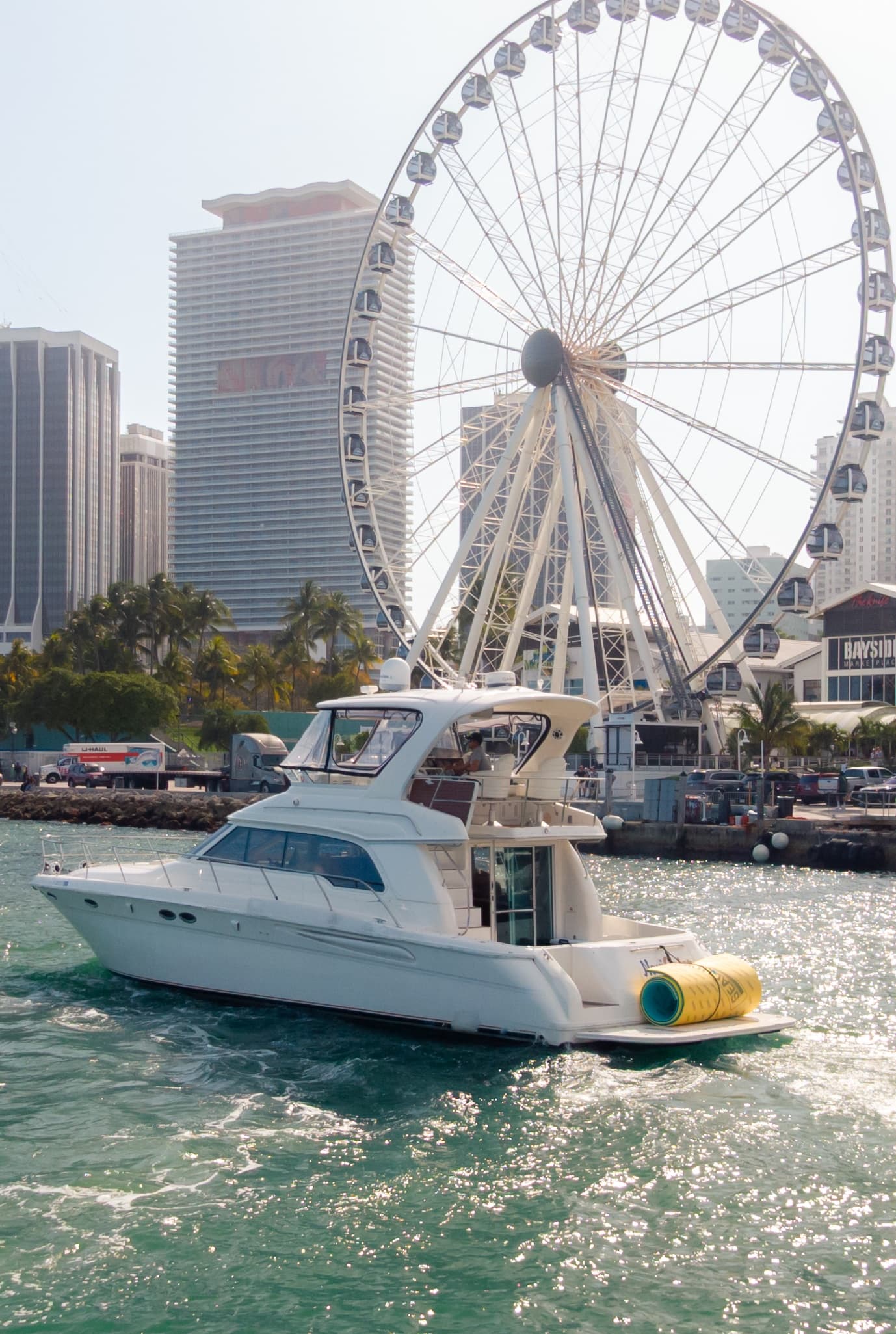 Motor yacht cruising near waterfront ferris wheel in city harbor