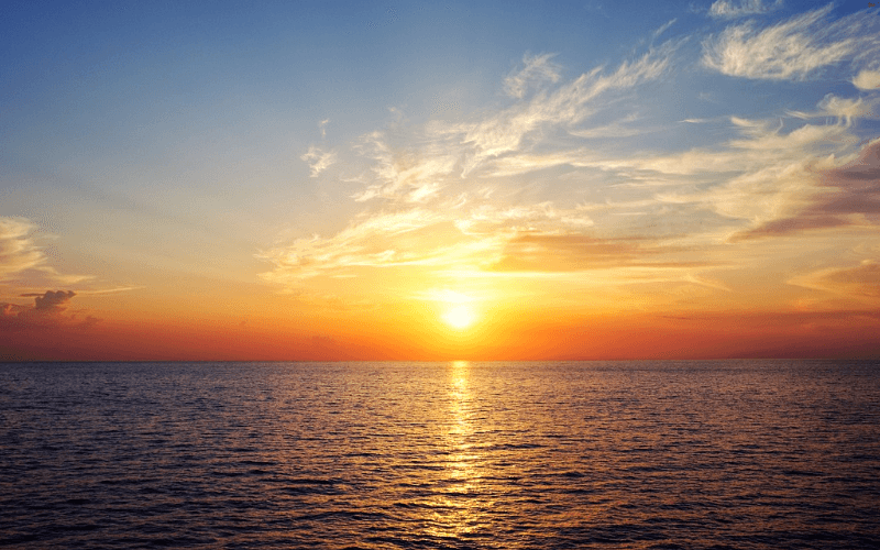 Sunset over open Pacific Ocean, calm waters and golden sky