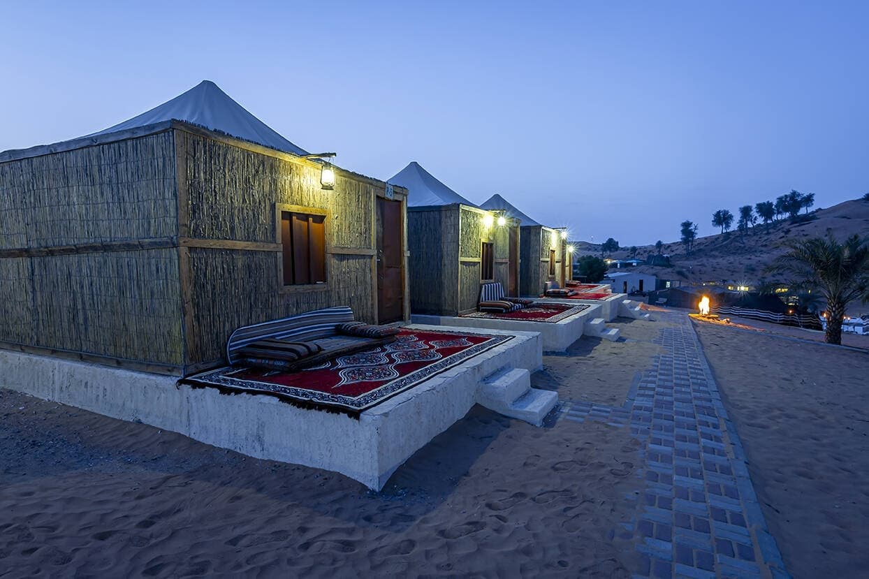 Traditional desert huts and outdoor seating at twilight camp