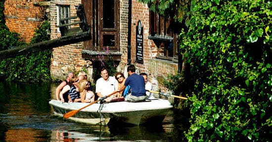 Group punting down scenic Canterbury river with lush banks