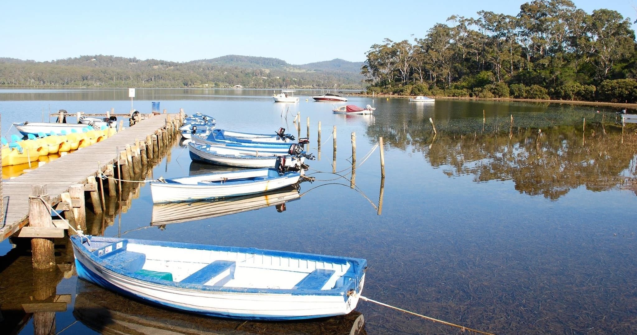 Small boats docked on calm estuary with reflective water view