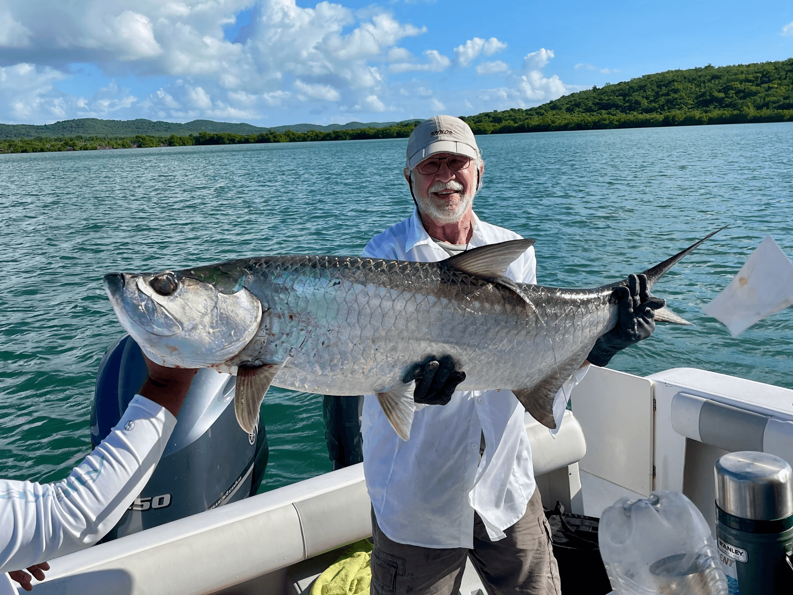 Angler holding large tarpon on fishing charter in coastal bay