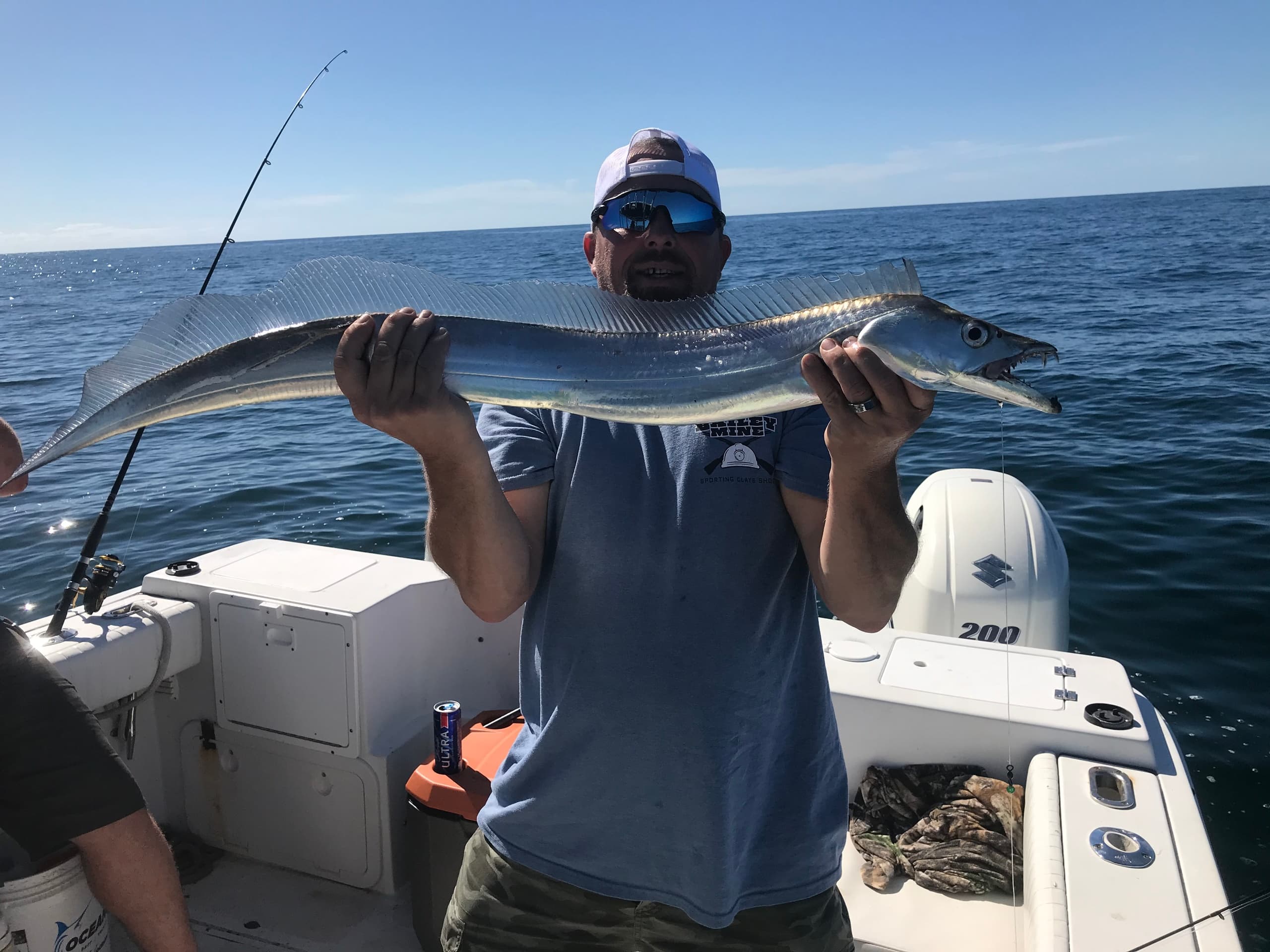 Angler holding long ribbonfish on charter boat in open sea