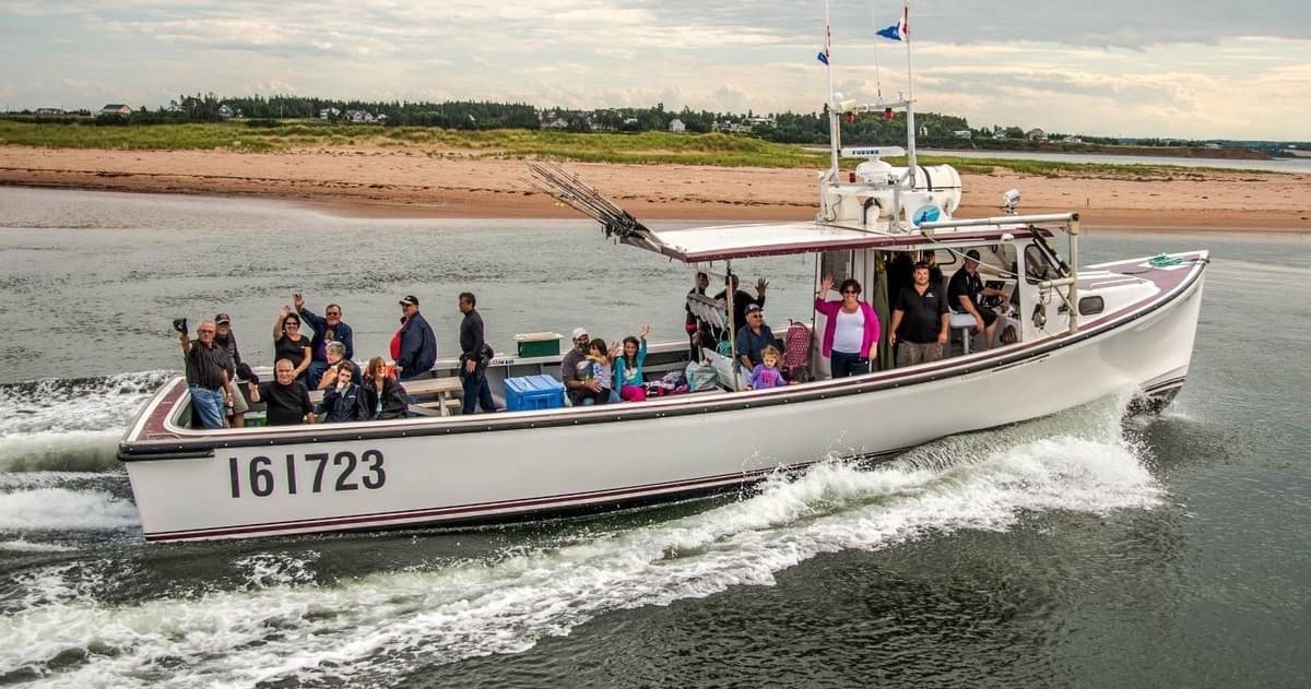 Fishing charter boat with passengers cruising near sandy shore