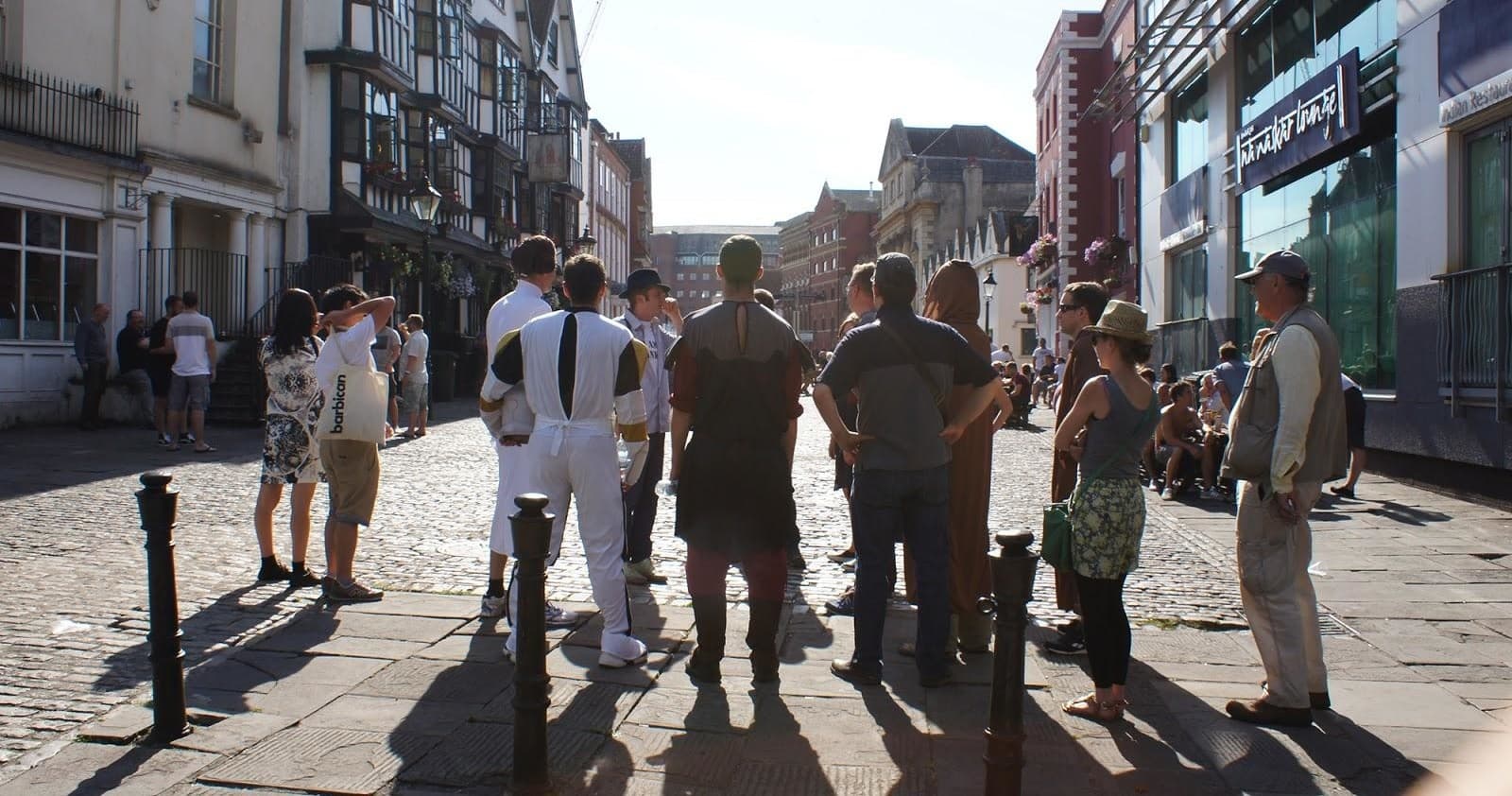 Walking tour group silhouetted on sunlit cobblestone street