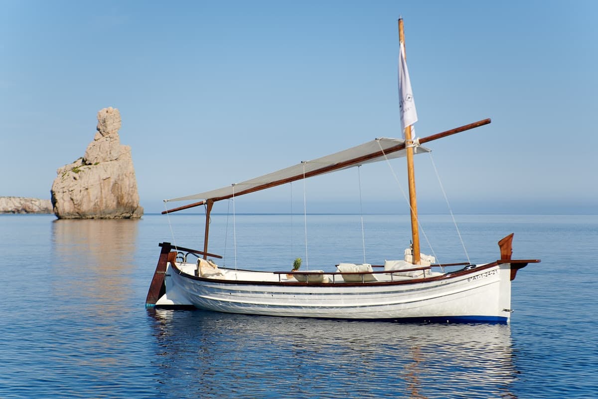 Traditional sailboat anchored off Ibiza coastline on calm sea