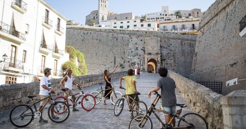 Group of cyclists exploring historic Ibiza old town walls