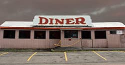 Closed diner facade beside highway evoking abandoned Americana road trip