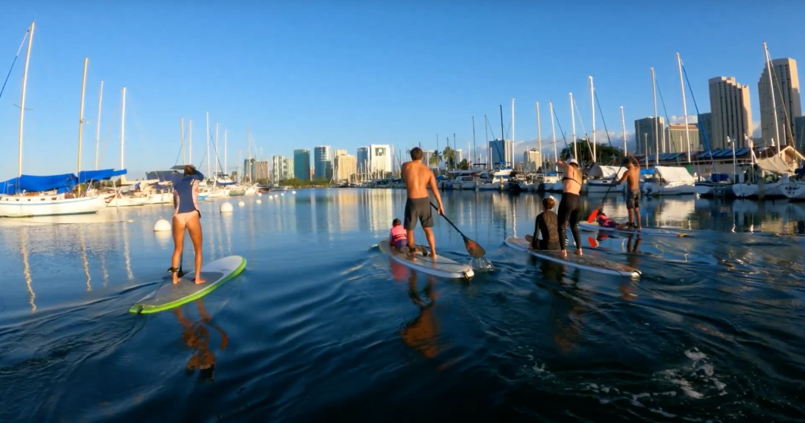 Standup paddleboarders in marina with city skyline in Hawaii