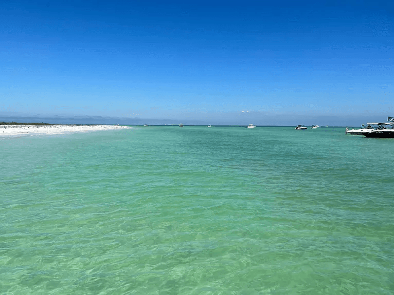 Crystal green coastal waters with boats and sandy shoreline