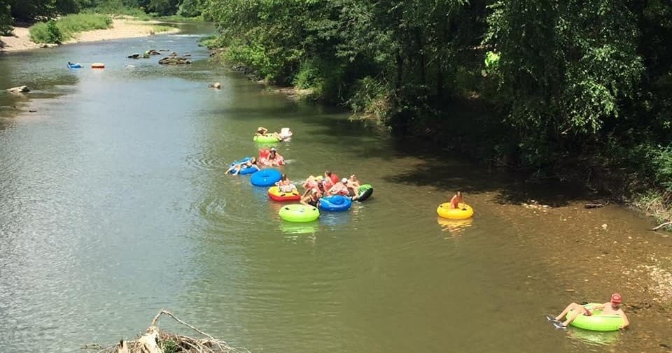 Families floating on colorful inner tubes down calm river