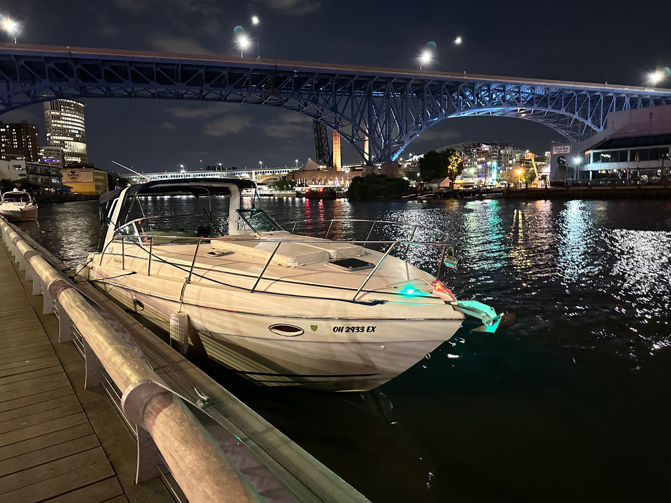 Parked powerboat at night under illuminated city bridge