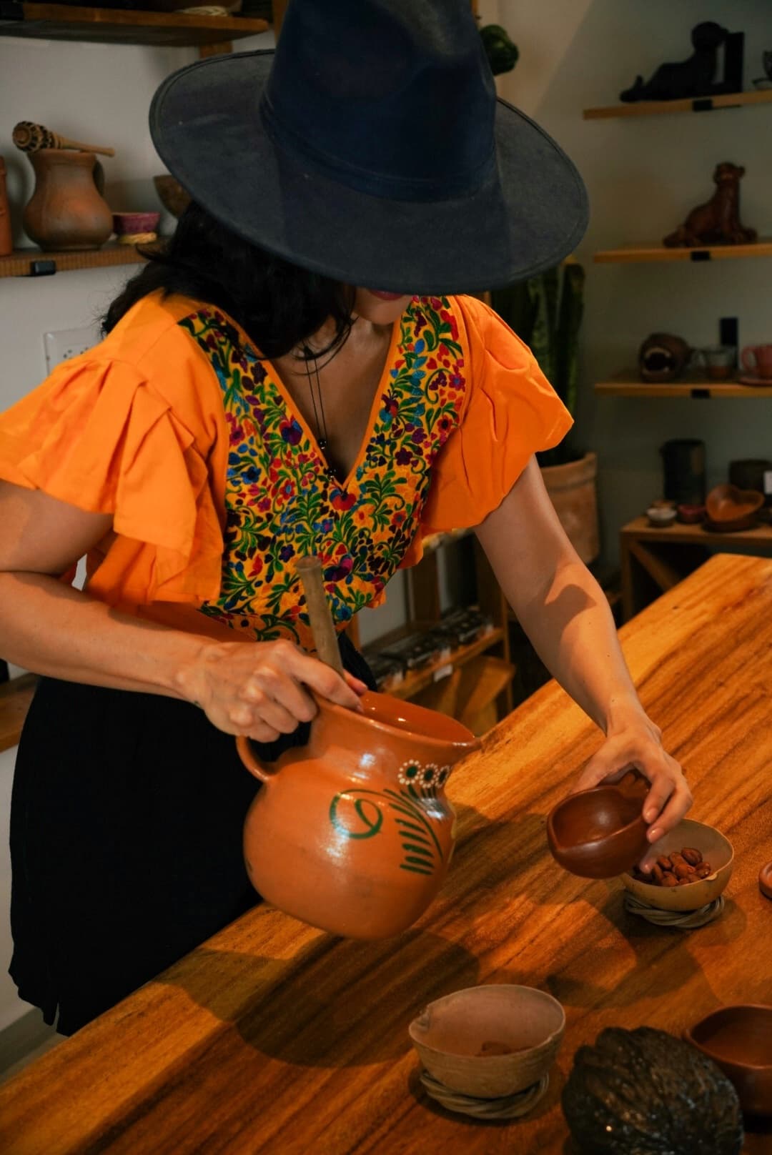 Guide pouring traditional Mayan chocolate from clay jug in Tulum shop