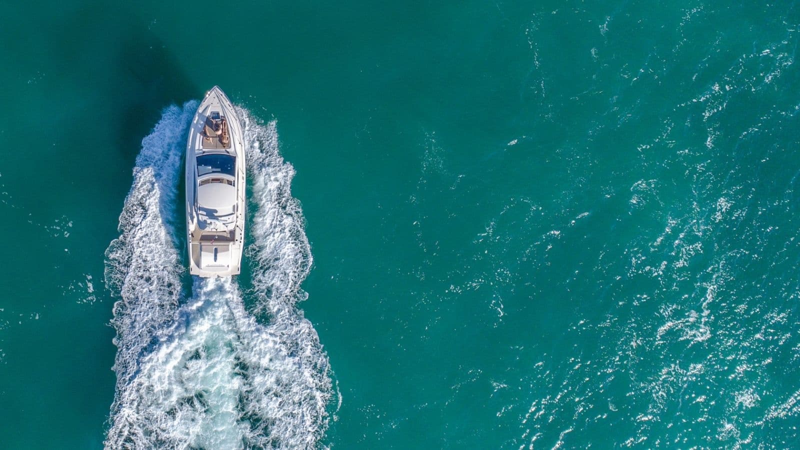 Motorboat cruising through turquoise open sea, aerial view