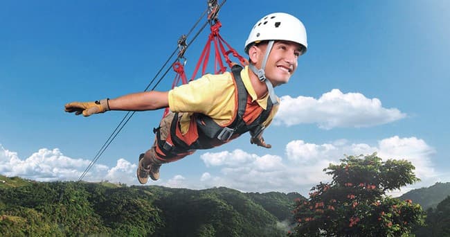 Young adventurer harnessed flying over mountain valley on zipline