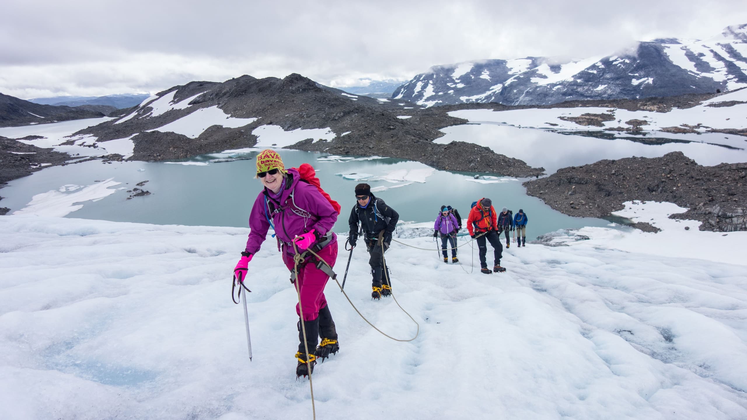 Group trekking across expansive blue glacier in daylight