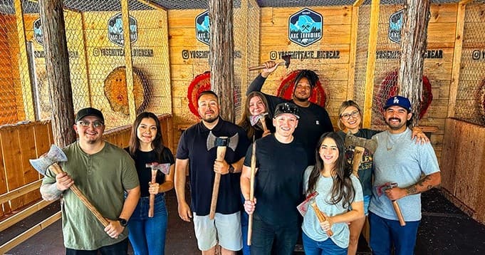 Smiling team holding axes at Yosemite Axe Throwing Big Bear range