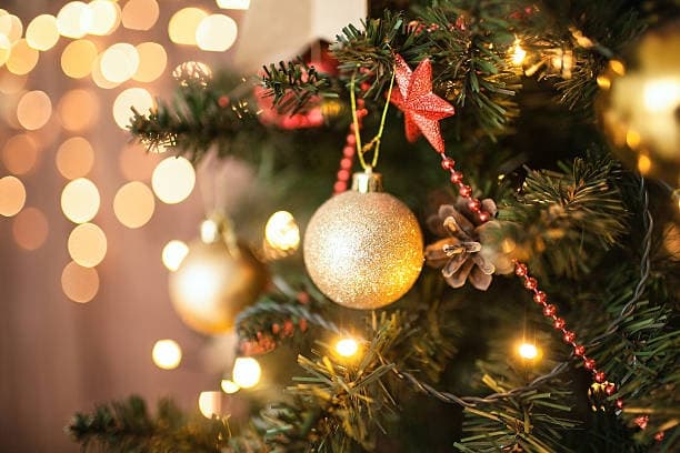 Decorated Christmas tree ornaments with warm bokeh lights indoors