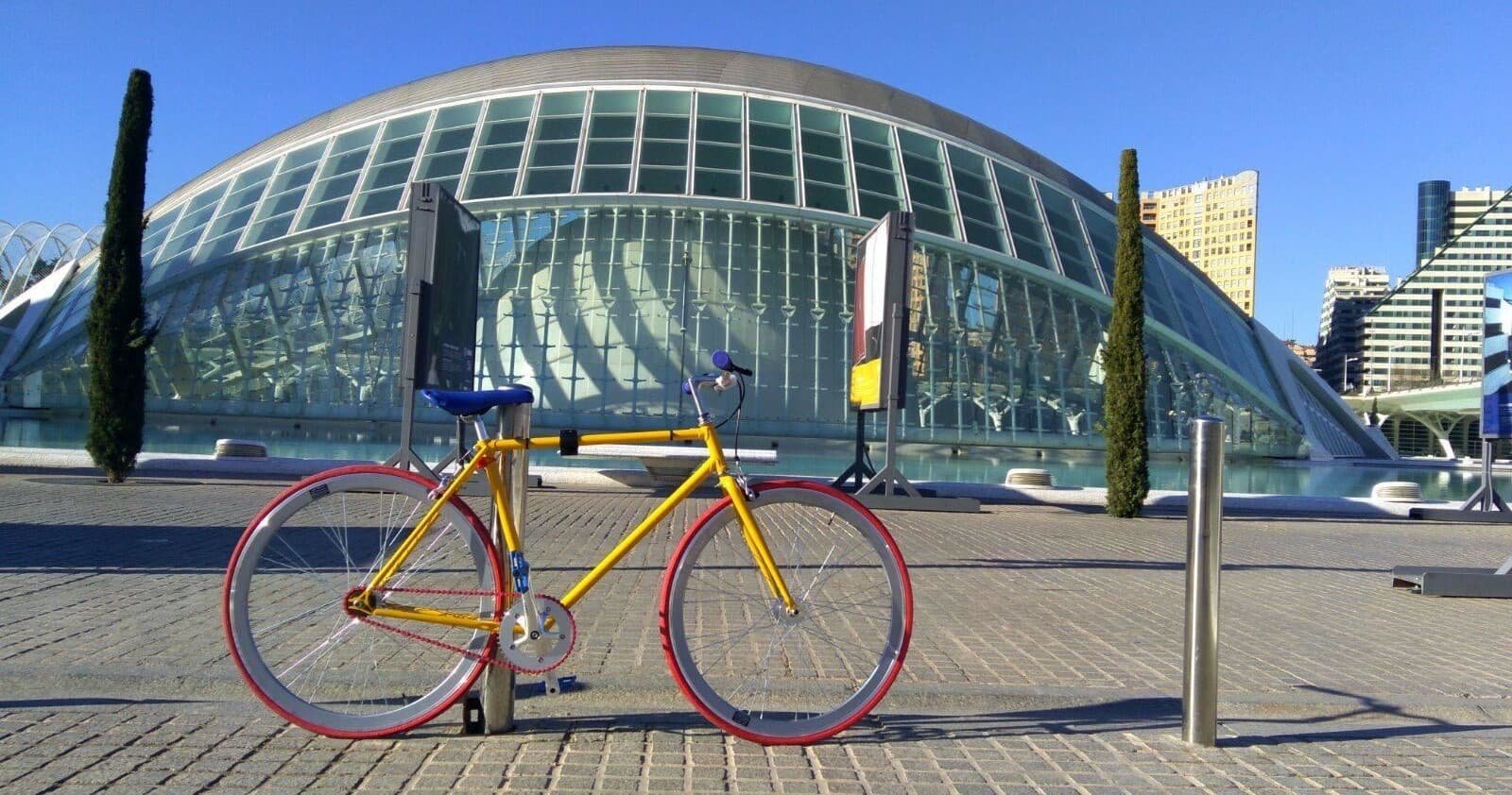 Yellow city bike parked by glass dome at urban waterfront plaza