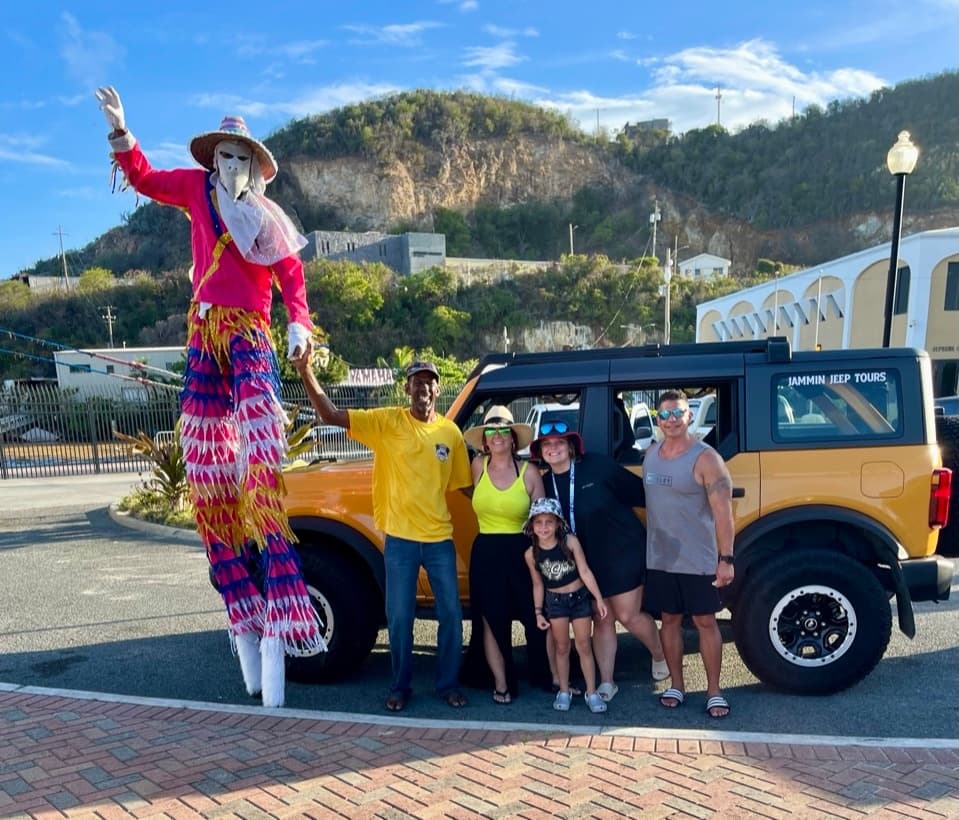 Tall stilt performer and jeep tour group posing with coastal hillside backdrop