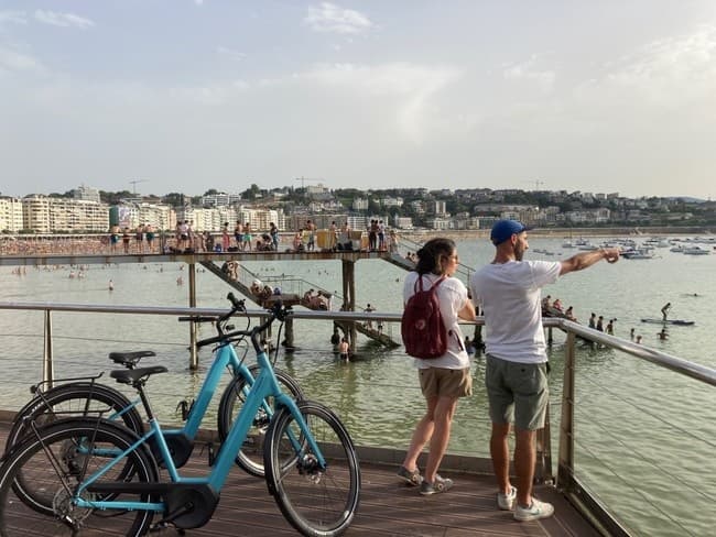 Couple pointing from pier with rental bikes overlooking harbor