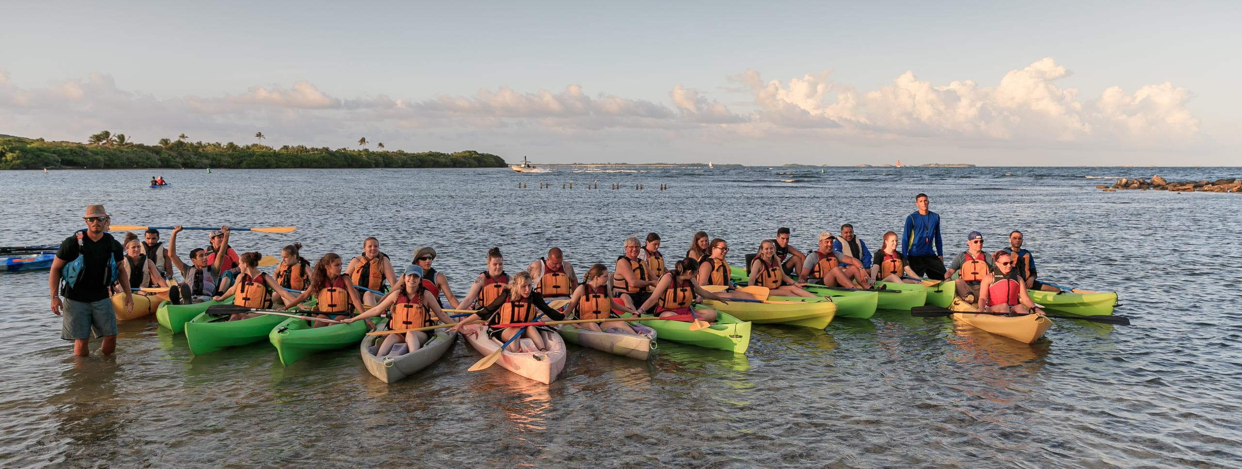 Large guided ocean kayak group paddling toward horizon