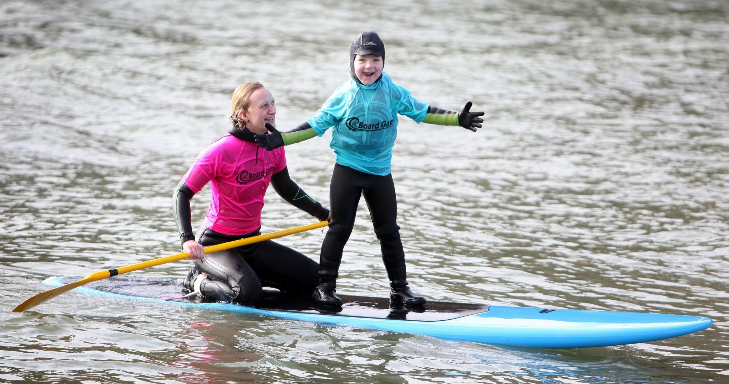 Instructor and child paddleboarding together on calm bay water