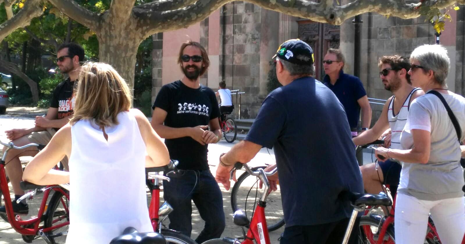 Group of cyclists gathering for Barcelona bike tour under trees