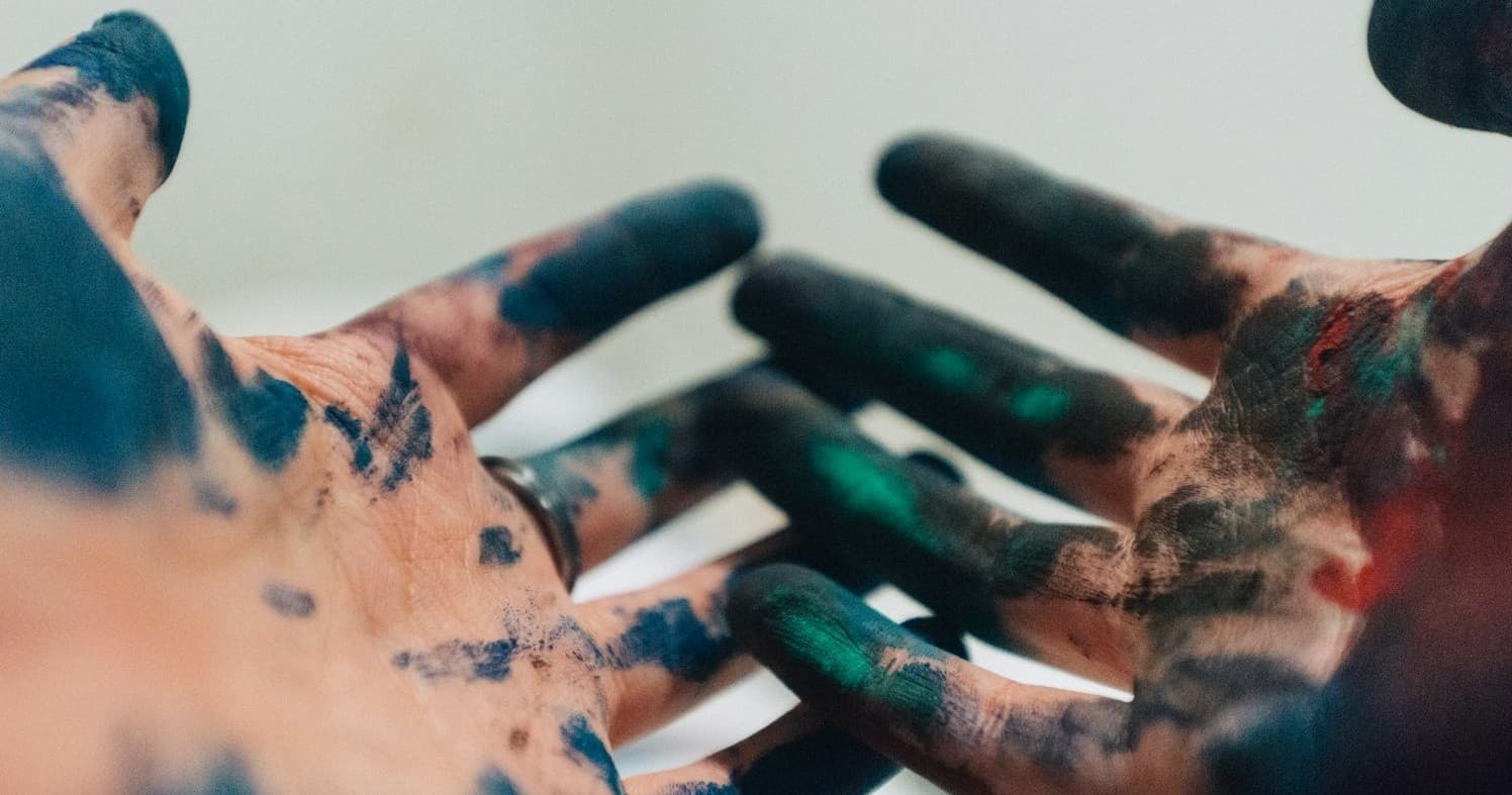 Hands covered in paint in indoor paint-smash room creative experience
