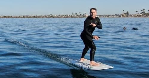 E-foiler riding a foil board on calm coastal ocean shore