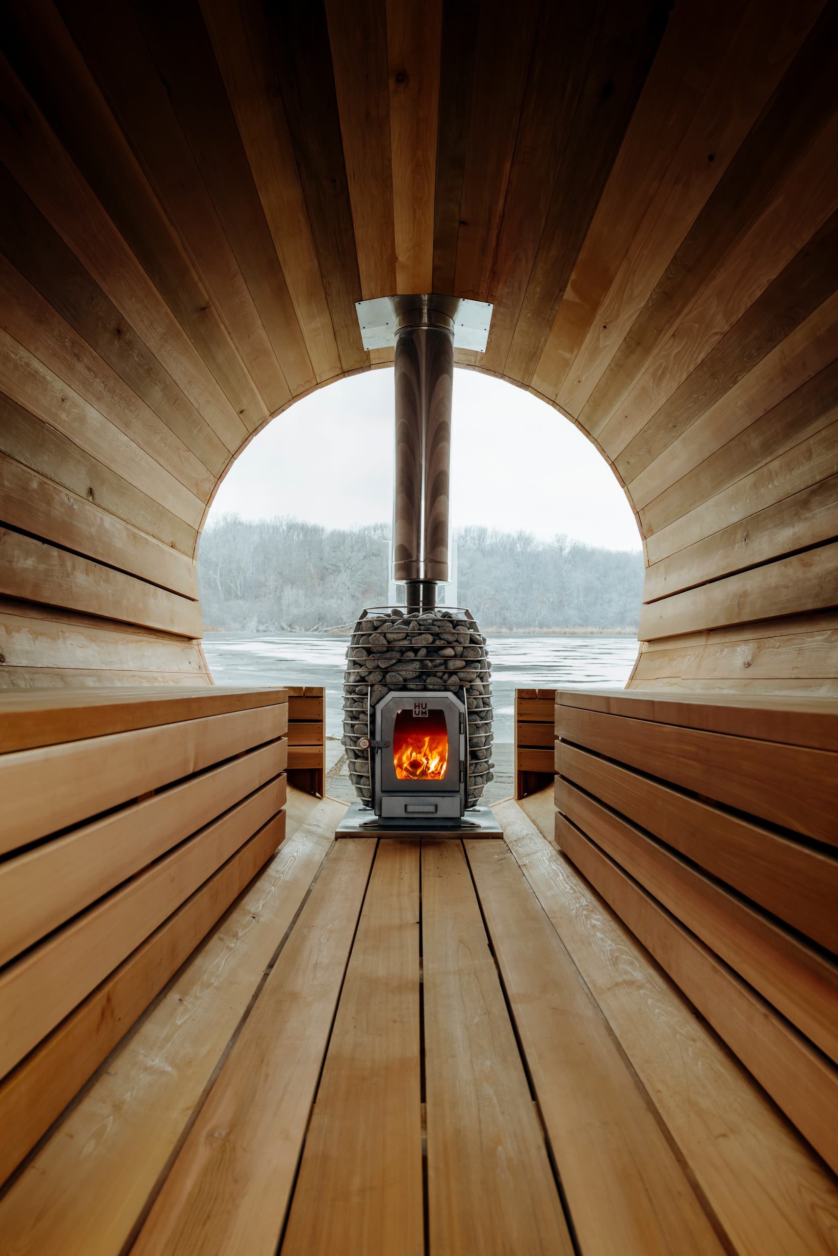 Interior view of barrel sauna with wood stove overlooking lake