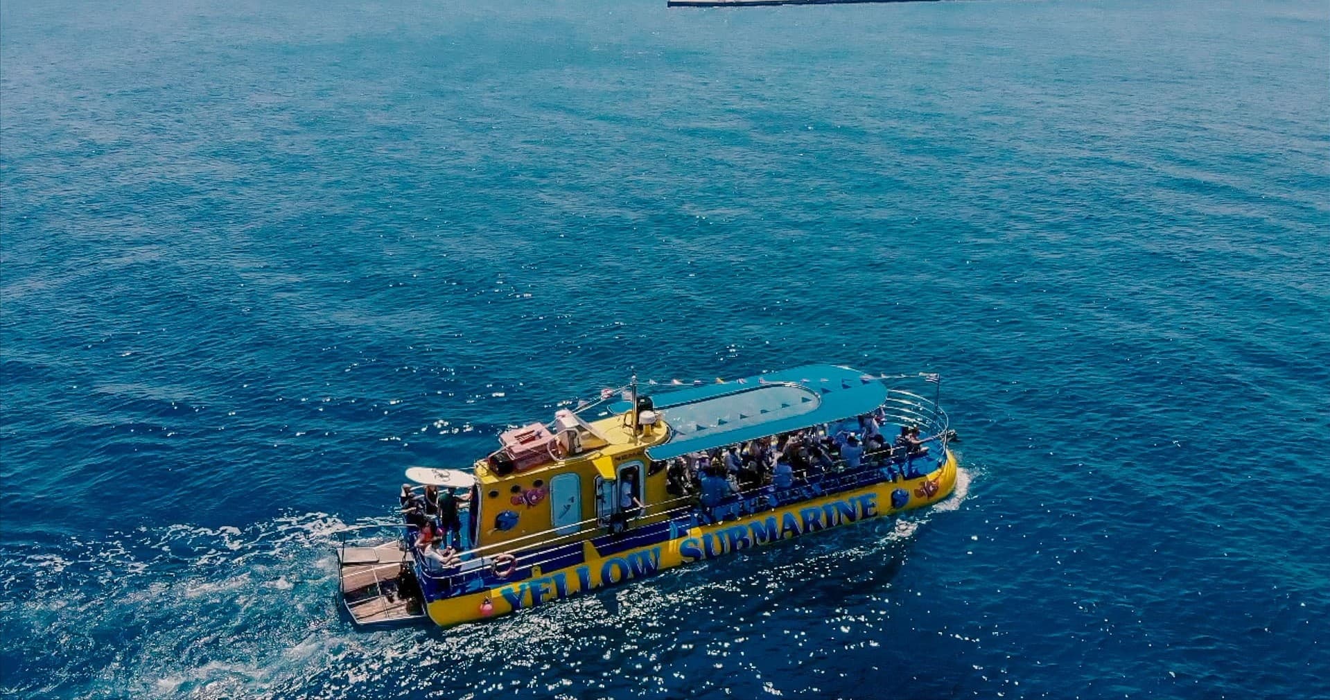 Yellow submarine tour boat cruising on clear open ocean with passengers