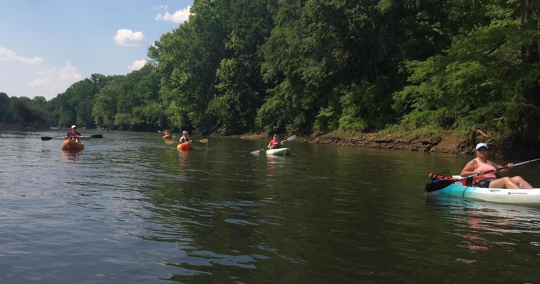 Paddlers kayaking along peaceful river bend with trees