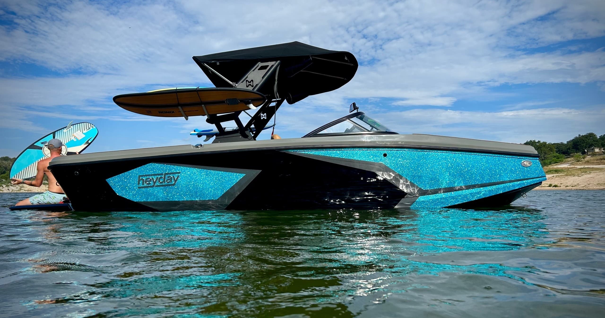 Blue speedboat with wake tower cruising clear blue waters