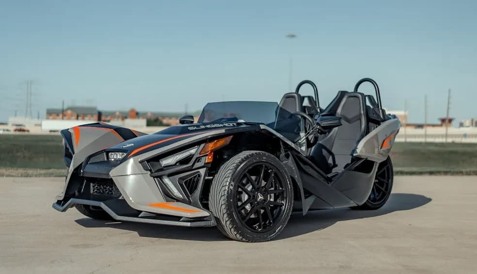 Two-seat Slingshot roadster on open pavement with clear sky