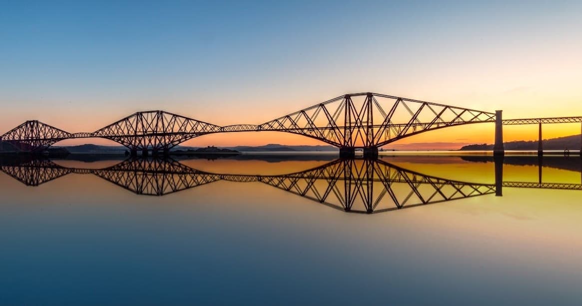 Sunrise view of Forth bridge reflecting over calm estuary