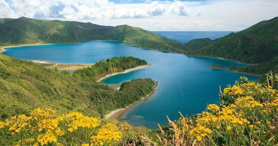 Scenic volcanic crater lake with wildflowers and waterfront views