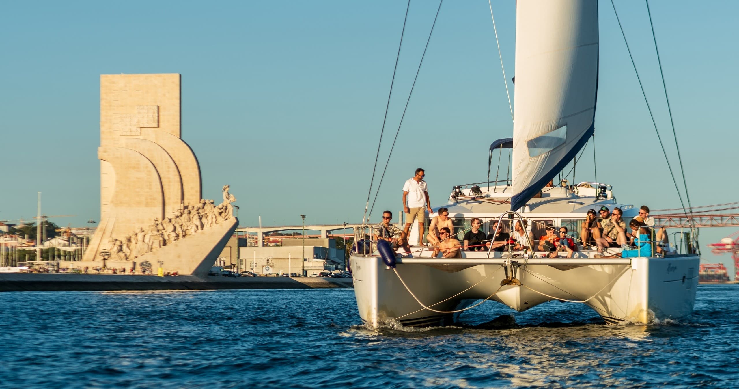 Catamaran tour passing coastal monument with happy passengers
