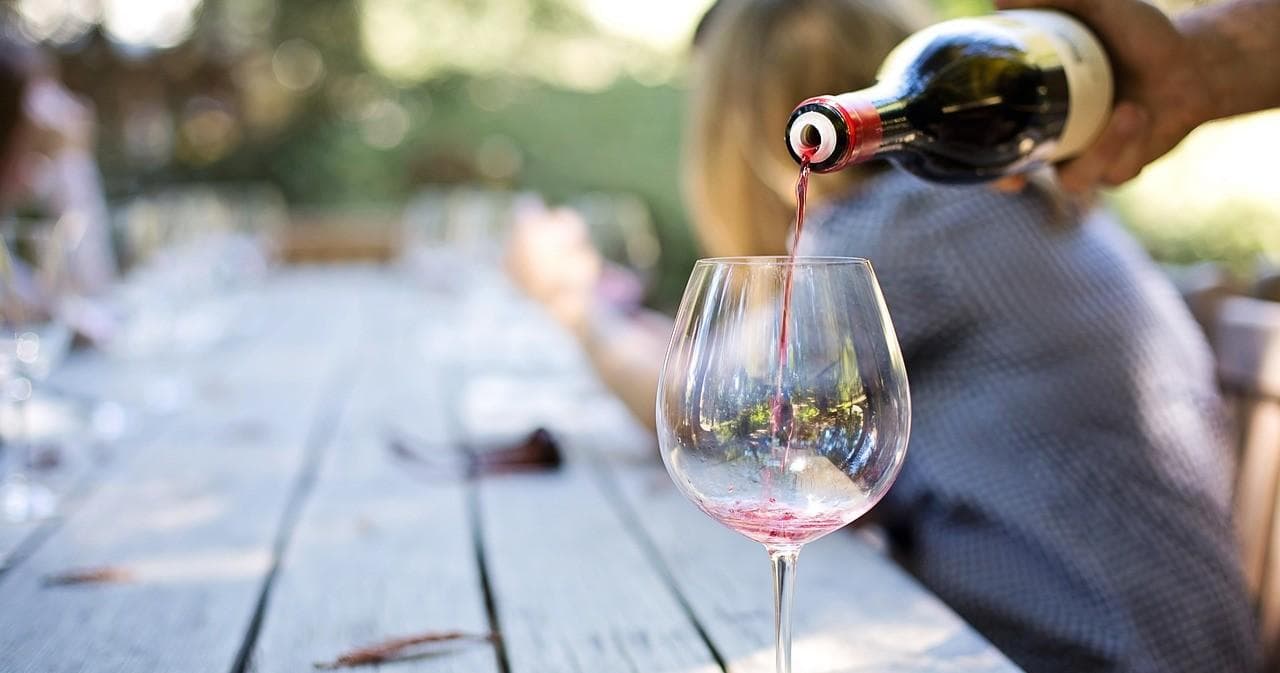 Outdoor picnic wine tasting, pouring red wine into glass