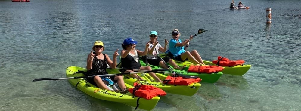 Family kayaking in clear shallow spring water, paddling together