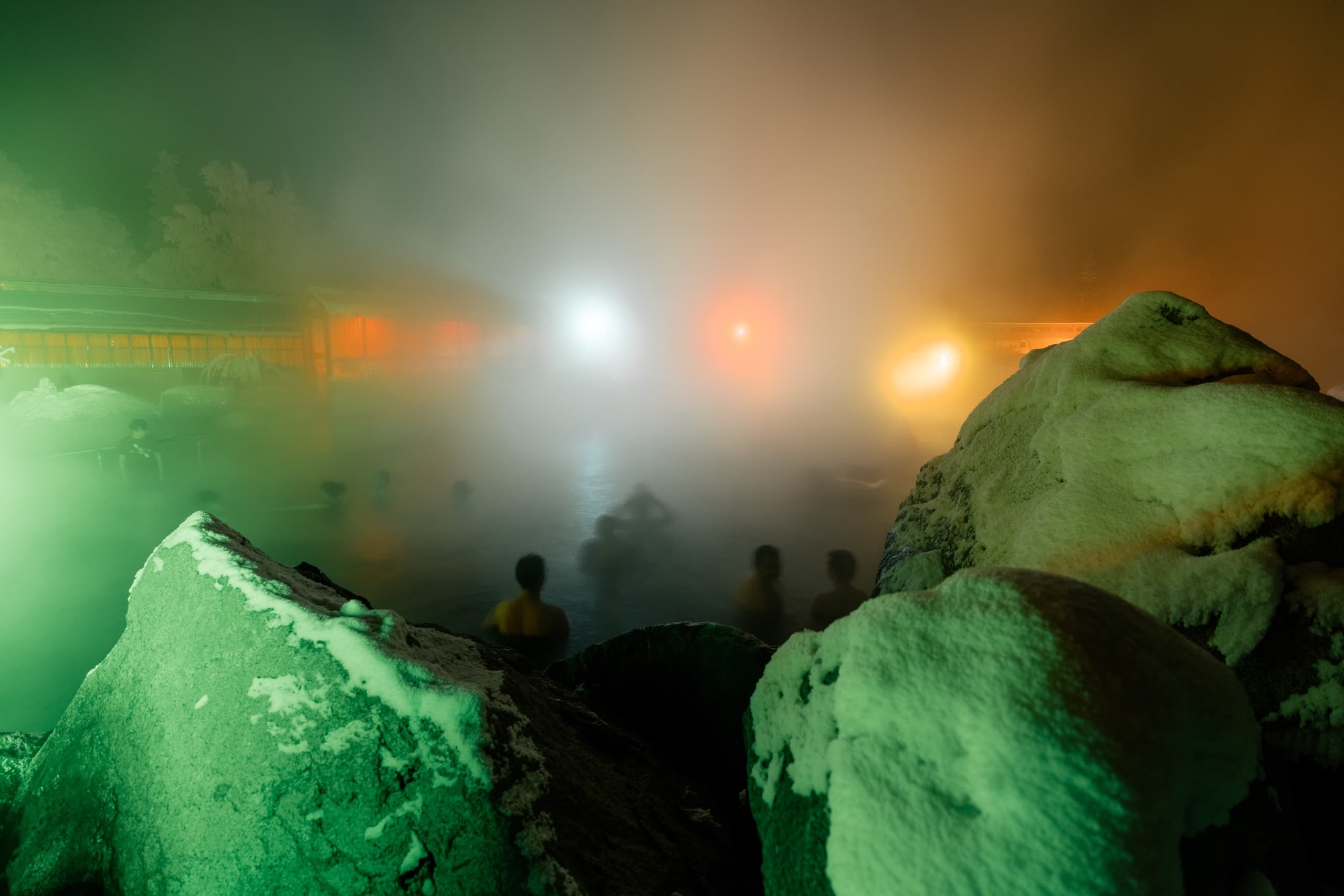 Nighttime hot springs soak with steam and colorful lights