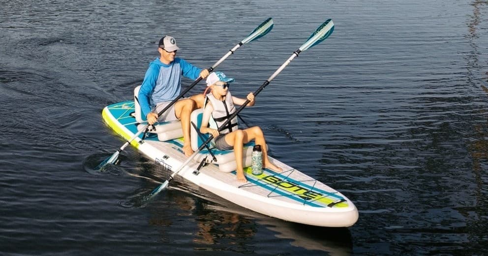 Two-person kayak paddling on calm dark coastal water, tandem experience