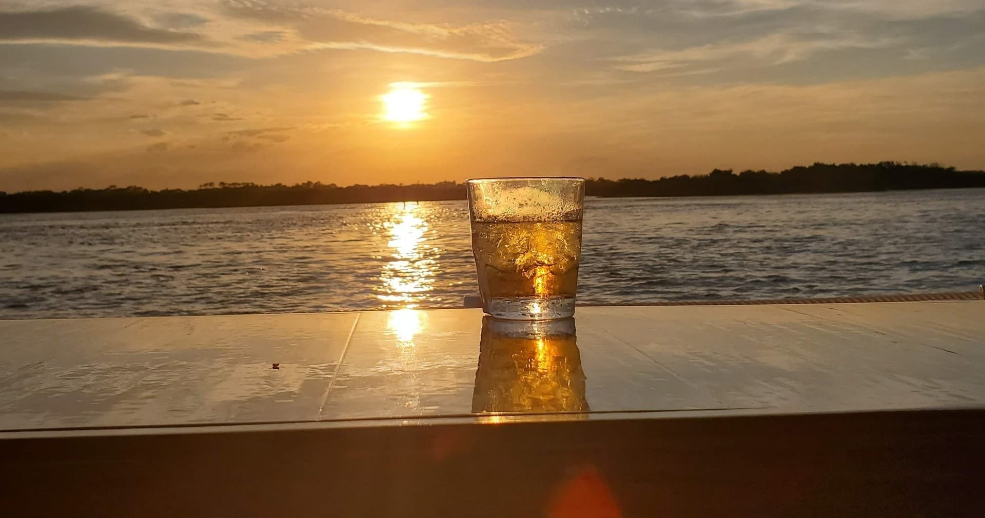 Sunset cocktail on waterfront table overlooking ocean horizon